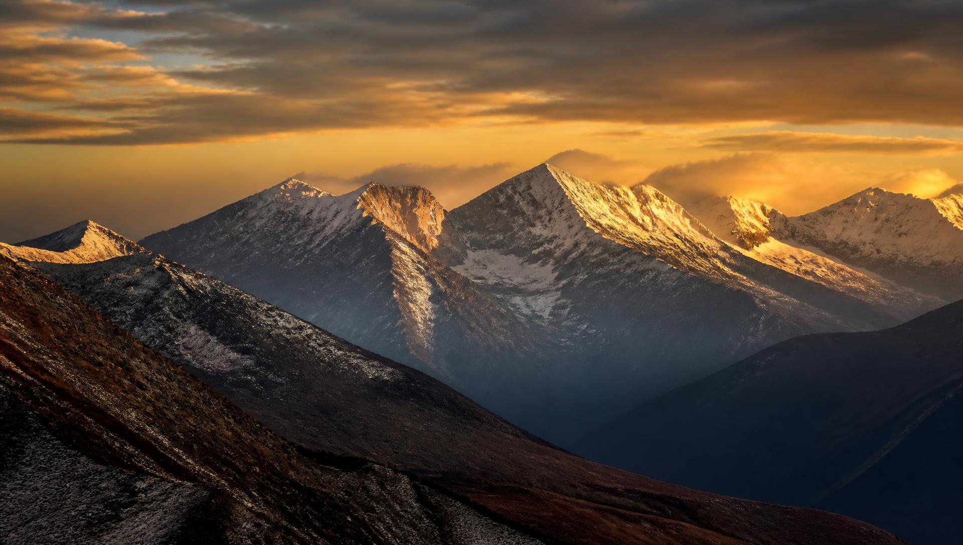 Dramatic snow-capped mountain range in Central Asia at golden hour