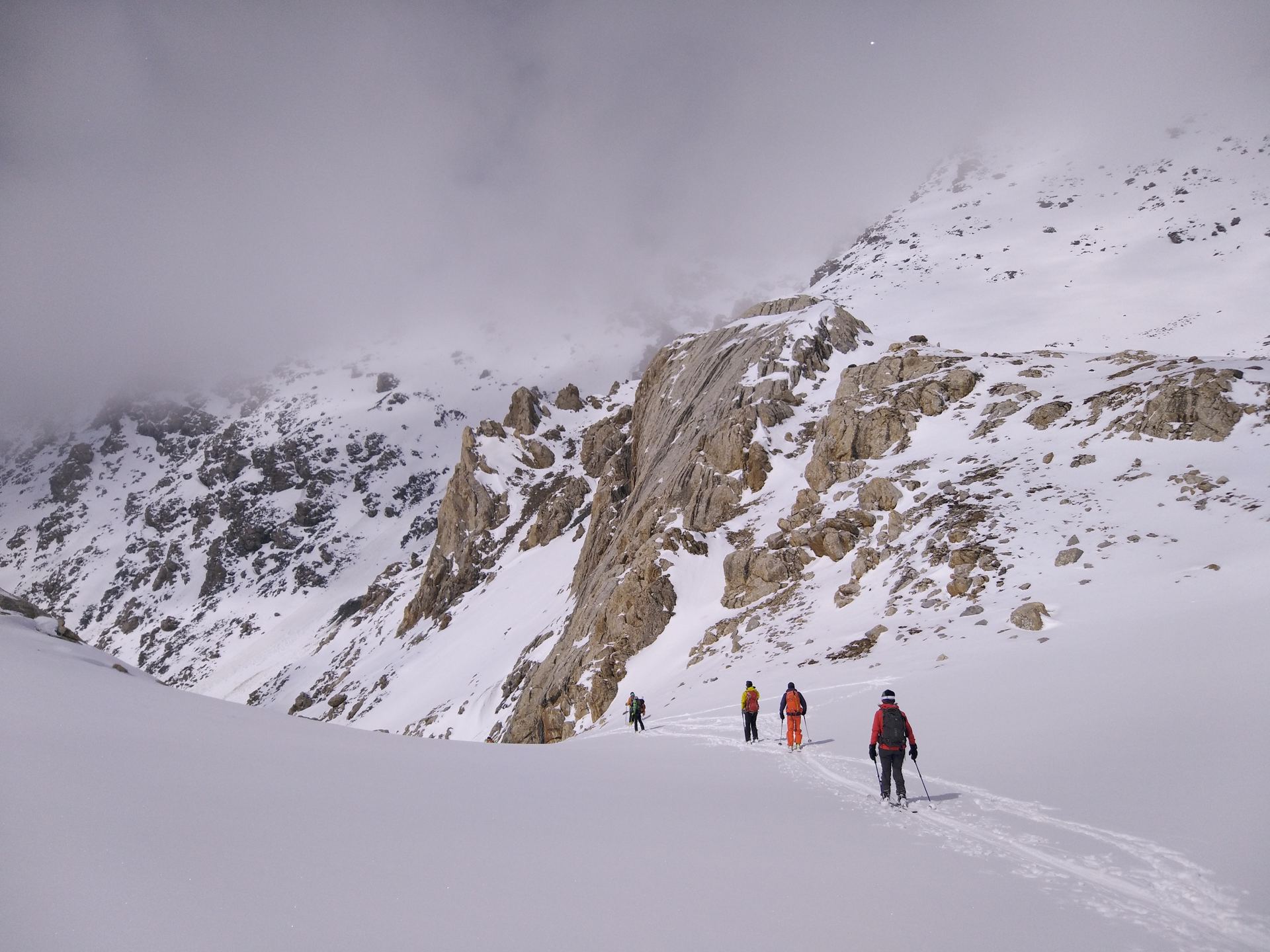 Line of trekkers crossing a snowfield below rocky, snow-covered slopes (partner-supplied Kyrgyzstan photo)